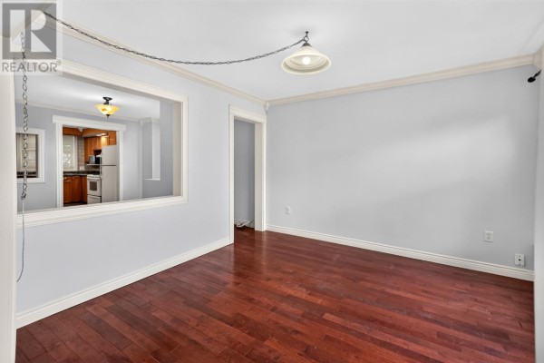 Empty room with dark wood floors, showing a pass-through to the kitchen. - 9 Malta Street, St  John S