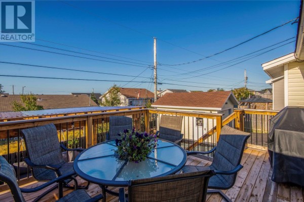 Wooden deck furnished with a glass-topped table and six chairs, overlooking neighboring rooftops. - 9 Mercedes Court, Conception Bay South