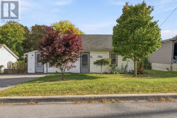 Front view of the white house with trees and green lawn. - 9 Rogers Street, Prince Edward County