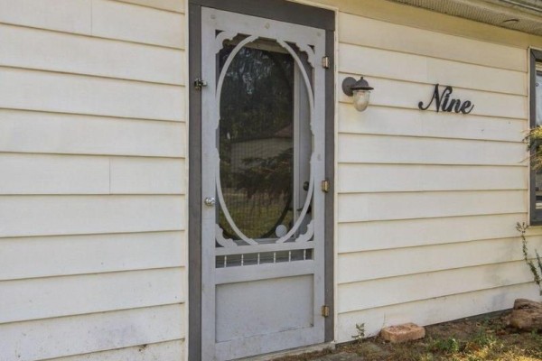 Close-up of a white screen door with decorative panel and the number nine. - 9 Rogers Street, Prince Edward County