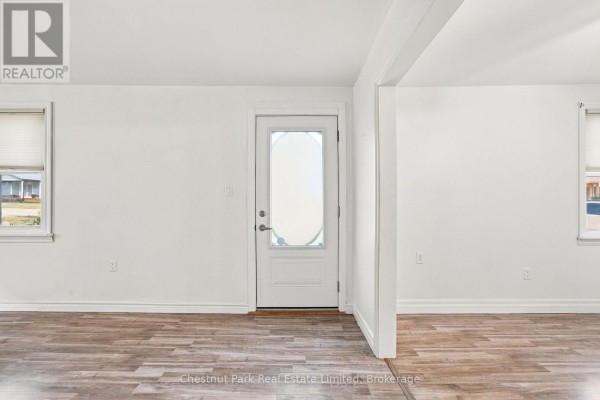 Interior view of an empty room with white walls and wood laminate flooring. - 9 Rogers Street, Prince Edward County