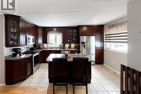 Kitchen with dark wood cabinets, granite countertops, stainless steel appliances, and an island. - 9 Stanley Street, Campbellton