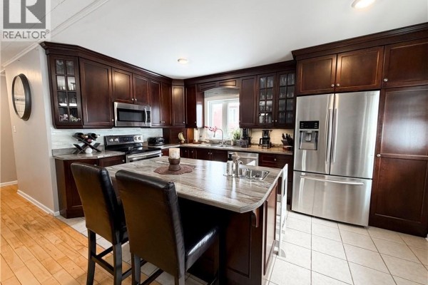 A spacious kitchen featuring dark cabinetry, stainless steel appliances, and a marble-topped island. - 9 Stanley Street, Campbellton
