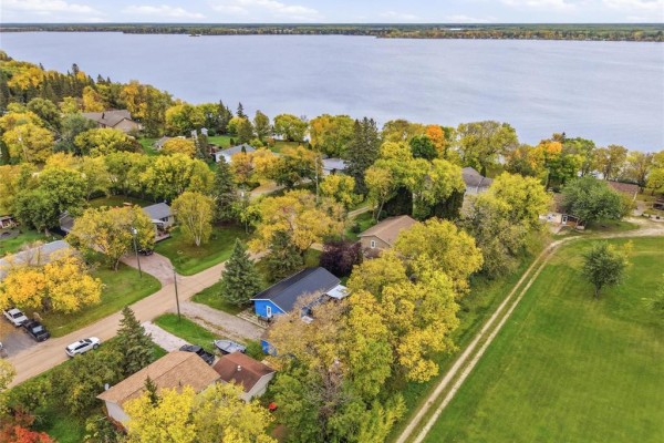 Aerial view of the neighborhood with multiple houses, trees, and the lake on the horizon. - 9 Tanco Crescent, Lac Du Bonnet