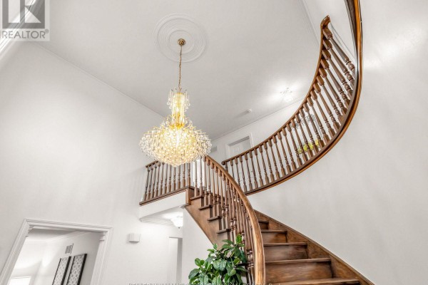 View of the grand wooden staircase with ornate balusters and a crystal chandelier. - 9 Tigerlily Court, Toronto