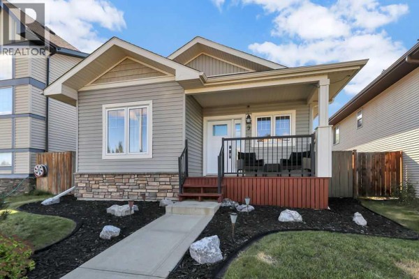 View of the front of the house with a paved walkway and landscaped yard. - 9 Valley Crescent, Blackfalds