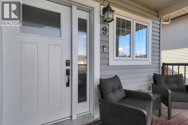 Detail of the white front door, window, and porch with dark wicker chairs. - 9 Valley Crescent, Blackfalds