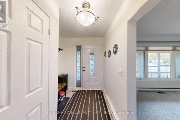 Interior foyer with white doors, a black and white striped rug, and a small shoe bench. - 9 Vaughan Avenue, Port Hope