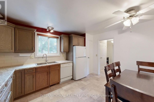 Kitchen with dark red walls, wood cabinets, white tile backsplash, and beige flooring. - 9 Vaughan Avenue, Port Hope
