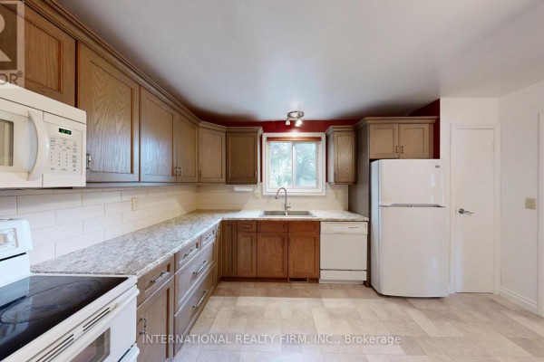 View of the kitchen from the side, showing a white refrigerator, dishwasher, and wood cabinets. - 9 Vaughan Avenue, Port Hope