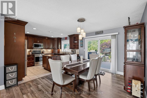 Dining area with a dark wood table, upholstered chairs, and a sliding glass door opening to the backyard. - 9 West Street N, Norwich