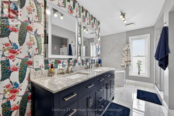 Bathroom vanity with a marble countertop, double sinks, and bold peacock-themed wallpaper. - 9 West Street N, Norwich