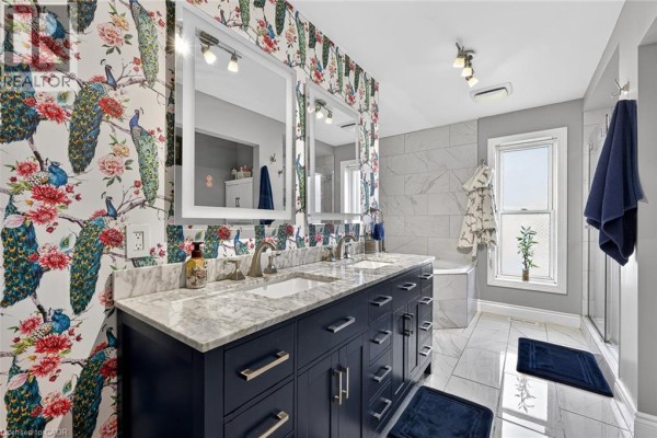 Luxurious bathroom with a double vanity, marble countertop, peacock wallpaper, and tiled shower and bathtub. - 9 West Street N, Springford