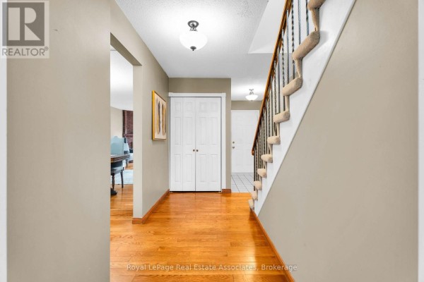Interior hallway with beige walls, hardwood floor, a white double door closet, and a carpeted staircase with railing. - 9 Windwood Drive, Toronto