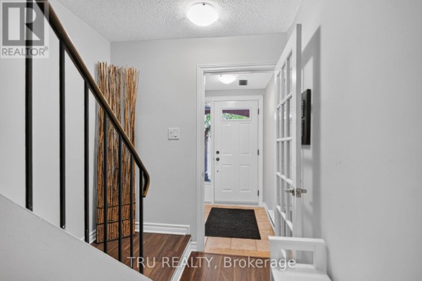 Interior view of a hallway with a staircase and a door to the outside. - 90 - 50 Lightfoot Place, Ottawa