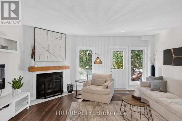 Living room with a fireplace, sofa, armchair, and large windows. - 90 - 50 Lightfoot Place, Ottawa