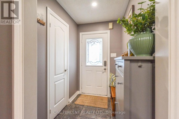 Interior entryway with grey walls, a white door, grey storage cabinet, and glass-paned door. - 90 Breeze Drive, Bradford West Gwillimbury