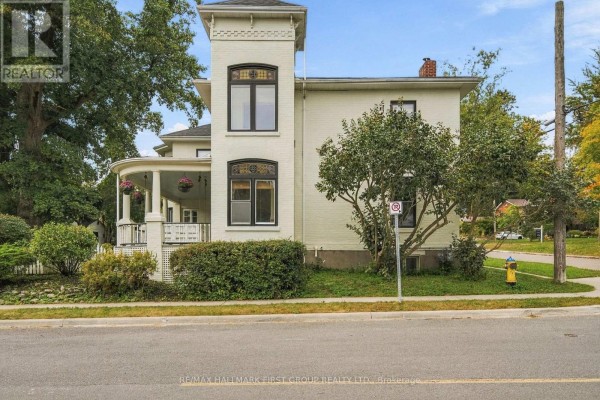 Side view of a cream-colored house with a distinctive tower and paved sidewalk. - 90 Brown Street, Port Hope