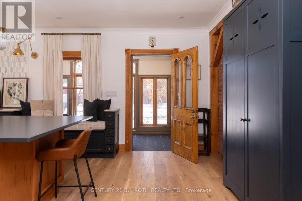 Interior view of a kitchen area with an island, wooden door, and natural light - 90 Cumberland Street, Barrie
