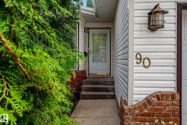 Front entrance with a white door, concrete steps, and house number 90 on siding. - 90 Dufferin St, St  Albert