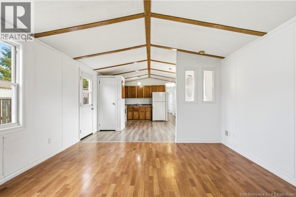 Interior living area with wood laminate flooring, white walls, and vaulted ceiling. - 90 Eastwood Street, Fredericton