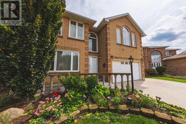Close-up of the front entrance of a brick house with a stone garden and outdoor lighting. - 90 Fairington Crescent, Hamilton