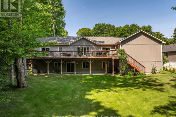 Rear view of the home with a large wooden deck overlooking a grassy backyard. - 90 Graham Crescent, South Bruce Peninsula