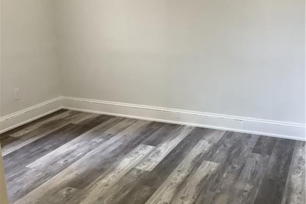 Empty room with light gray walls and grey wood-look vinyl plank flooring. - 90 Kent Street S Unit# 4, Simcoe