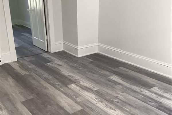 Corner of a room with gray wood-look vinyl plank flooring and white trim around doorway. - 90 Kent Street S Unit# 4, Simcoe