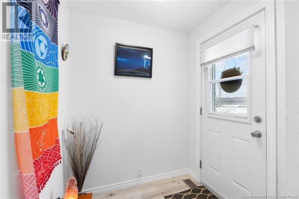 Interior entryway with white walls, white door, a framed picture, and colorful wall hanging. - 90 King Street, Chipman