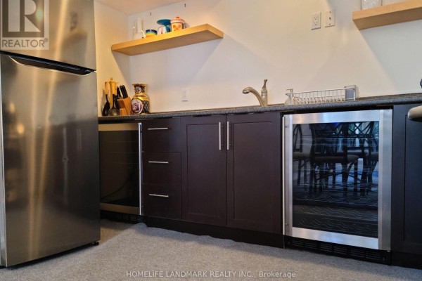 Kitchenette with dark wood cabinets, stainless steel refrigerator, wine fridge, and granite countertops. - 90 Marsden Court, Newmarket