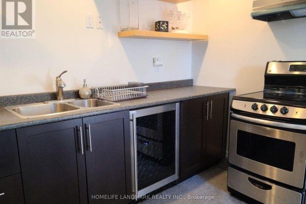 Kitchenette with dark wood cabinets, stainless steel double sink, wine fridge, and stainless steel stove. - 90 Marsden Court, Newmarket