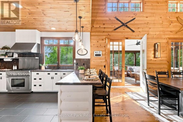 Kitchen with island seating, stainless steel range, and wood paneling - 90 Swallowdale Road Huntsville