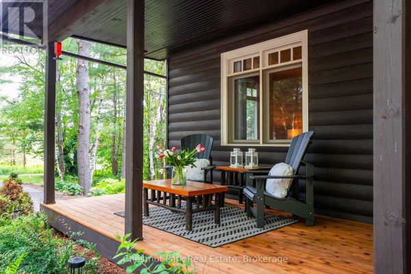 Covered front porch with Adirondack chairs, coffee table, and flowers - 90 Swallowdale Road Huntsville