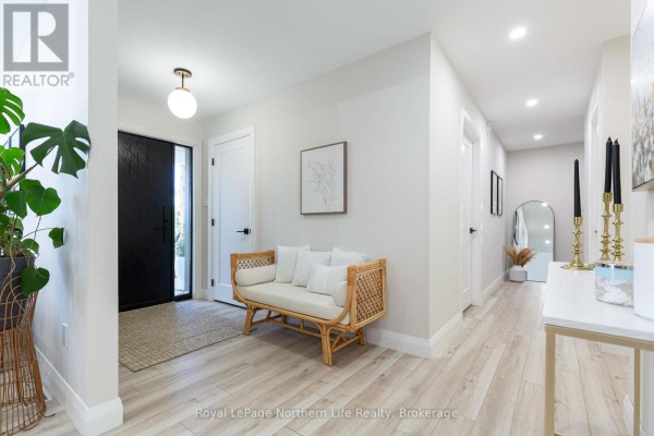 Wide angle view of bright foyer with black door, bench, and hallway. - 90 Young Drive, Powassan