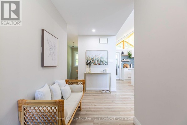 Hallway looking toward kitchen, featuring light wood floors and a console table. - 90 Young Drive, Powassan