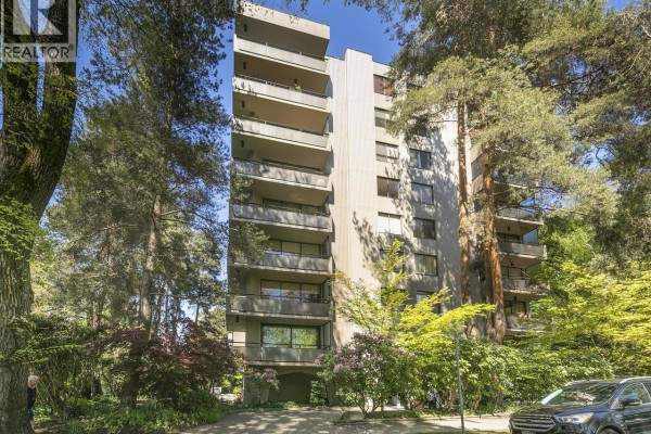 Exterior of a concrete apartment building with balconies and mature trees. - 900 1685 W 14th Avenue, Vancouver