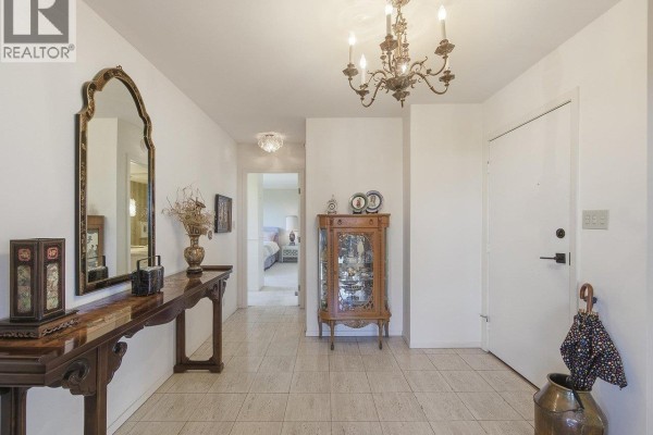 Apartment entryway with tiled floors, ornate mirror, console table, and chandelier. - 900 1685 W 14th Avenue, Vancouver