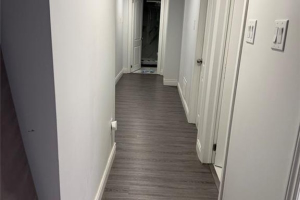 Hallway with light grey walls, white doors, and dark grey wood-look laminate flooring. - 900 Kennedy Road, Scarborough
