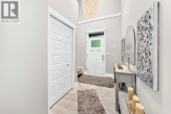 Interior entryway with light grey walls, white bi-fold closet doors, and a console table. - 901, 110 Coopers Common Sw, Airdrie