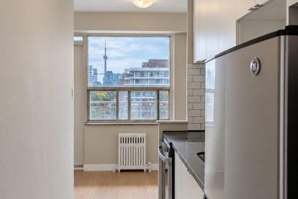 Kitchen details including a refrigerator and stove, with a view of the Toronto skyline. - 901 - 206 St George Street, Toronto