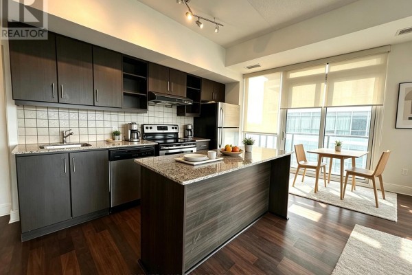 Kitchen with dark wood cabinets, granite countertops, island, and small dining area. - 901 - 35 Brian Peck Crescent, Toronto