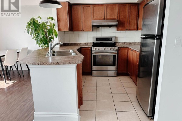 U-shaped kitchen with wood cabinets, stainless steel appliances, and tiled flooring. - 901 - 935 Sheppard Avenue W, Toronto