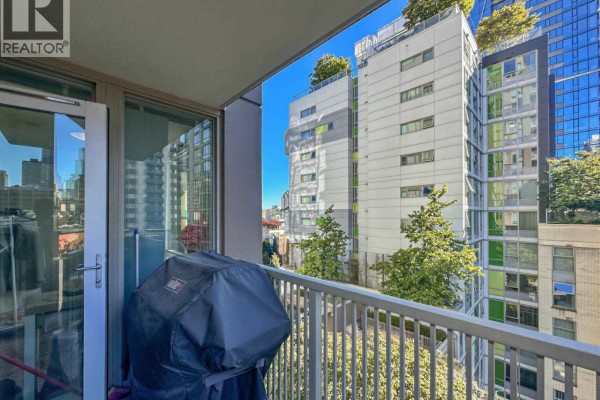 Balcony view featuring a covered grill and city buildings through a metal railing. - 901 1055 Richards Street, Vancouver