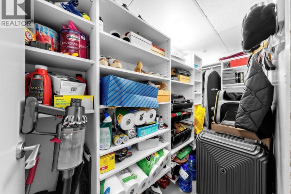 Walk-in closet with white shelving filled with shoes, cleaning supplies, and luggage. - 901 1055 Richards Street, Vancouver