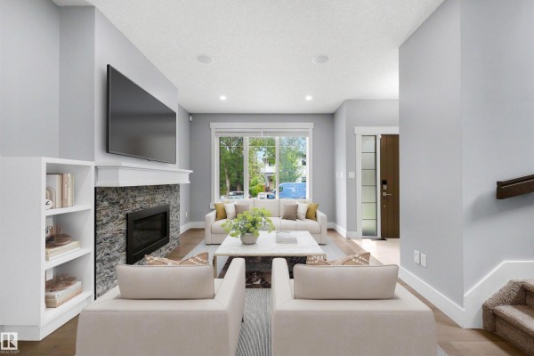 Living room with a large window overlooking the street, fireplace, and white built-in shelves. - 9013 90 St Nw, Edmonton