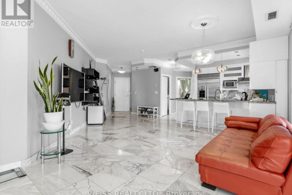 Living room with television, red sofa, and open kitchen with island. - 902 - 18 Beverley Street, Toronto