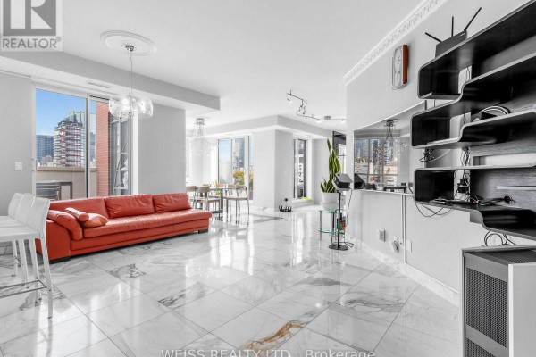 Spacious living area with red sofa, city views, and modern shelving unit. - 902 - 18 Beverley Street, Toronto