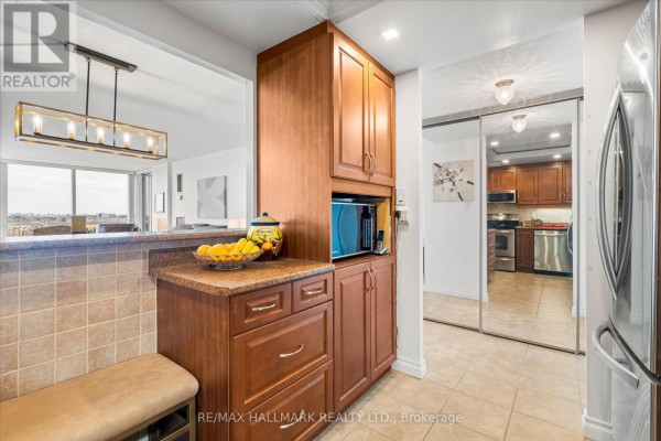Bedroom with king-size bed, white bedding, built-in white cabinets, and television. - 902 - 20 Dean Park Road, Toronto