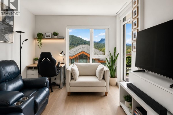 Modern kitchen with light wood cabinets, white quartz countertops, and a breakfast bar with stools. - 902 1210 E 27th Street, North Vancouver